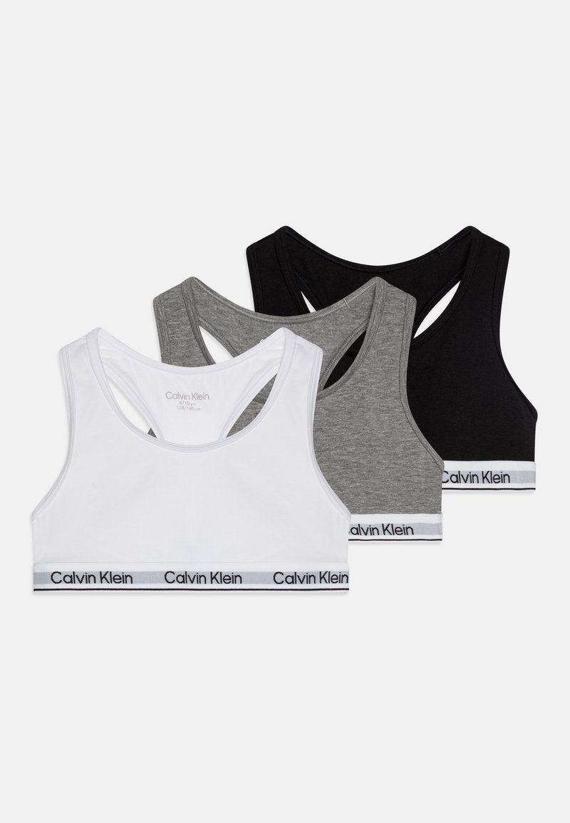 Tri suknje za sport u bijeloj, sivoj i crnoj boji. Svaka ima dizajn s leđima u obliku trkača i pojas s natpisom "Calvin Klein" ispisanim u crnoj i sivoj boji.