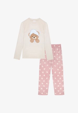 Blød cremefarvet langærmet top med en bjørn med et håndklæde på hovedet, parret med lyserøde bukser med et hvidt hjertemønster.