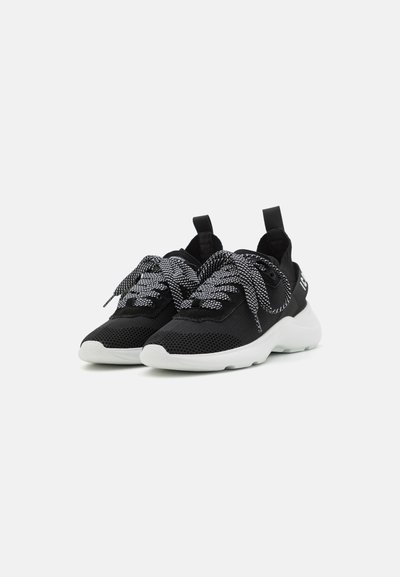 Sneaker in rete nera con suola bianca, caratterizzate da lacci testurizzati neri e bianchi, un tassello sulla parte posteriore e un design slanciato.