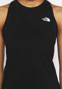 Svart ärmlös linne i mjukt tyg, med en liten vit logotyp av "The North Face" på bröstet och rundad halsringning.