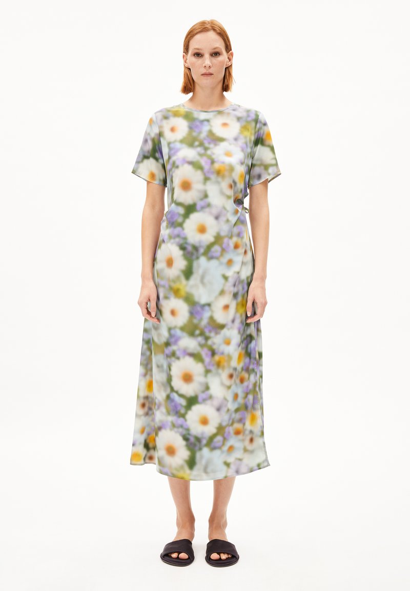 Midi-Kleid mit Blumenmuster aus leichtem Stoff, mit kurzen Ärmeln, das Gänseblümchen und Akzente in Lila und Gelb auf grünem Hintergrund zeigt.