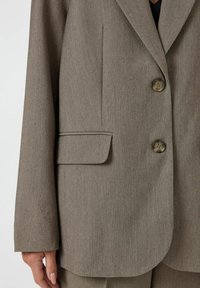 Bruine textuur blazer met twee grote knopen en een enkele borstzak, ontworpen met een klassieke snit en een relaxte pasvorm.
