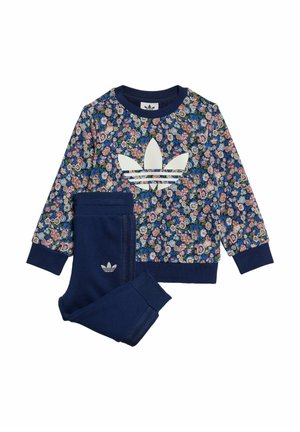 Børns todelte sæt med marineblå bukser og langærmet blomstret sweatshirt med stort hvidt Adidas-logo på brystet.
