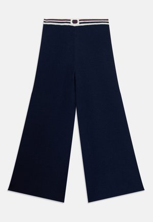 Weite marineblaue Hose aus einem weichen Material, mit einem gestreiften Bund und einem Knopfakzent in der Mitte.