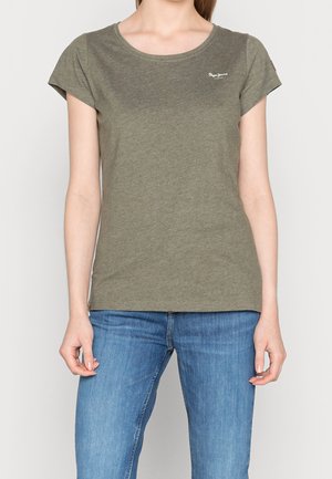 Oliwkowa zielona koszulka z miękkiej bawełny, krótki rękaw, okrągły dekolt, z małym logo na piersi, w połączeniu z ciemnoniebieskimi dżinsami.