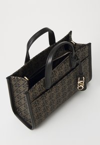 Borsa a tracolla marrone con motivo, rifinita in pelle nera, con doppi manici e un charm rimovibile con logo. Presenta una chiusura con zip e tasche interne.