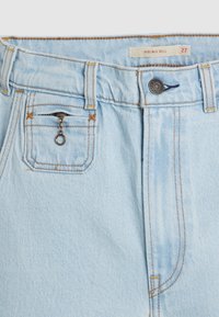 Jean bleu clair taille haute avec coutures orange, bouton en métal, braguette zippée et une petite poche zippée sur le côté droit.
