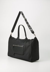 Sac de sport en nylon noir avec poignées doubles, bandoulière réglable et poche zippée à l'avant. Caractéristiques en métal argenté et design élégant.