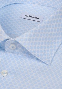 Col de chemise à motif bleu clair avec boutons blancs et étiquette blanche visible portant l'inscription « seidensticker » sur le col intérieur.
