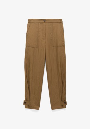 Brązowe, lekkie spodnie wykonane z teksturowanej tkaniny. Posiadają dwie przednie kieszenie, zapięcie na guziki oraz regulowane mankiety wokół kostek.