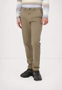Khaki chinos with a straight-leg design, featuring front pockets, a button closure, and a smooth, textured finish. Worn with black sneakers.