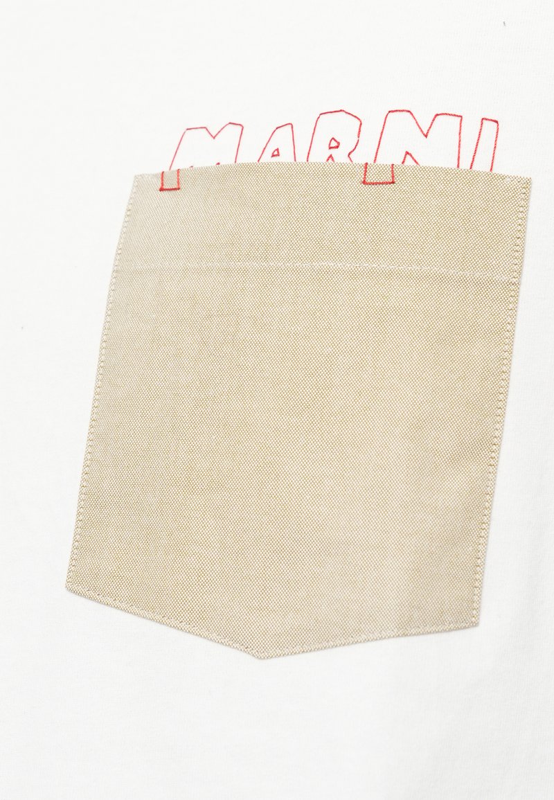 Weißer Stoff mit einer beigefarbenen Brusttasche, die teilweise rot gestickte Buchstaben mit "MARNI" über der Tasche abdeckt.
