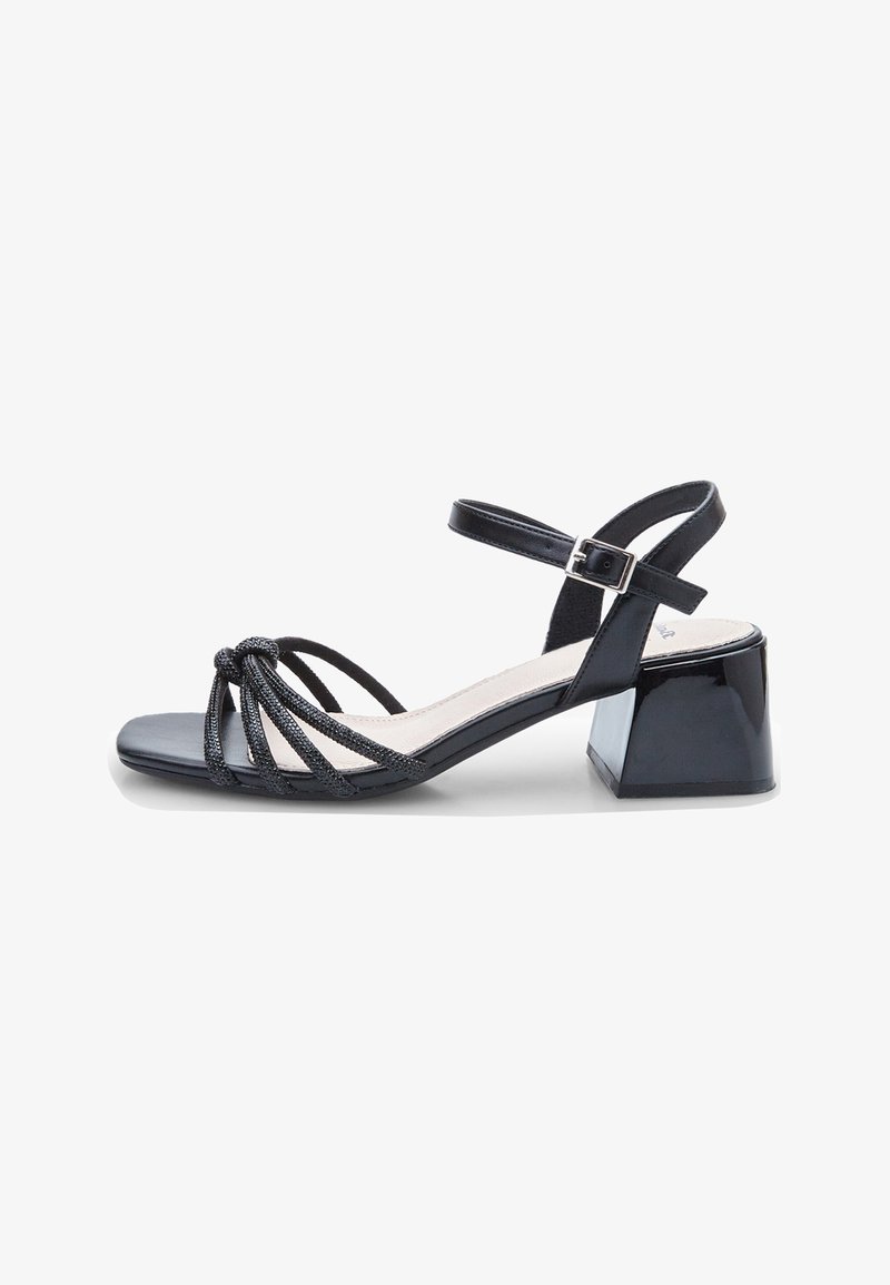 Black heeled sandal with a square toe, featuring multiple woven straps and an ankle buckle. Glossy block heel adds visual contrast.