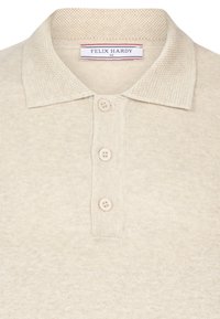 Beige gebreide polo met een gestructureerde kraag, een placket met drie knopen en een label met de tekst "FELIX HARDY" aan de binnenkant.