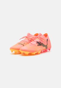 Fußballschuhe mit einem Farbverlauf in Rosa und Orange, einem Obermaterial aus Mesh, schwarzem Logo und einem genoppten Sohlenprofil für besseren Halt.