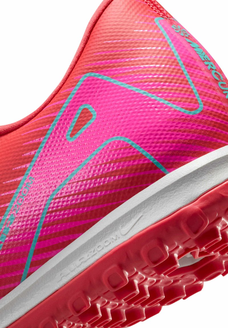 Chaussure de sport rose vif avec un matériau texturé, des accents blancs et bleus, un talon prononcé et une semelle en caoutchouc à motifs.