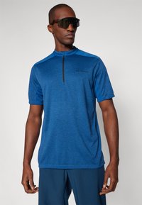 Camisola atlética azul feita de tecido texturizado, apresentando um colarinho elevado, design de meio zíper, mangas curtas e um pequeno logotipo no peito.