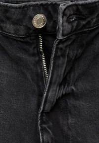 Gros plan sur un jean en denim noir avec une fermeture éclair argentée partiellement ouverte et un bouton métallique à la taille.