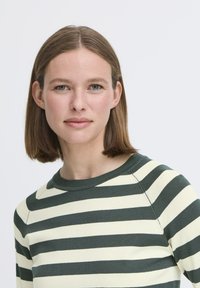 Suéter a rayas con rayas horizontales alternas en verde oscuro y crema, cuello redondo y textura de punto suave.