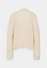 Off-white, stickad tröja med boxig form, långa ärmar och en texturerad, fluffig yta. Inga synliga stängningar eller dekorationer.