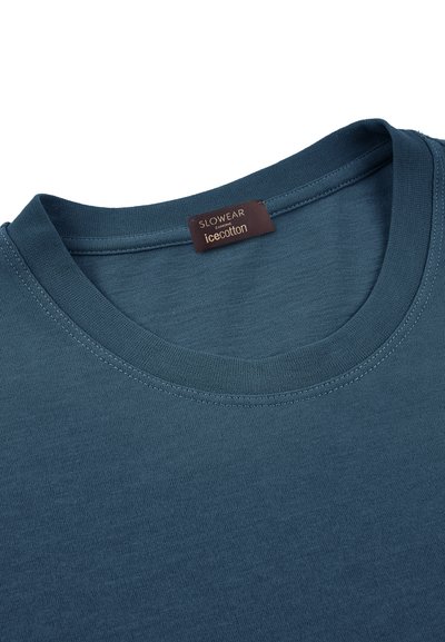 Camiseta azul de cuello redondo con una etiqueta marrón visible en el interior del cuello que dice "SLOWEAR ZAMONE icecotton."