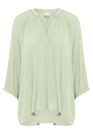 Lichtgroene blouse met een ontspannen pasvorm, ronde halslijn en driekwart mouwen. Voorzien van knopen aan de voorkant en zachte, vloeiende stof.
