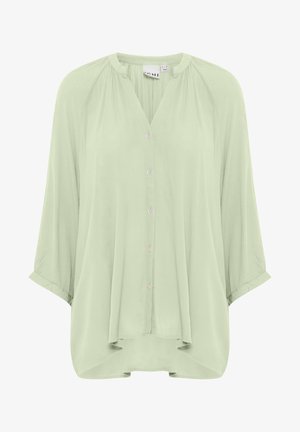 Lichtgroene blouse met een ontspannen pasvorm, ronde halslijn en driekwart mouwen. Voorzien van knopen aan de voorkant en zachte, vloeiende stof.