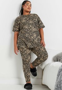 Set med två delar för avkoppling, bestående av en topp med kort ärm och leggings, båda med ett djurmönster i svart och beige. Mjuk tygkvalitet.