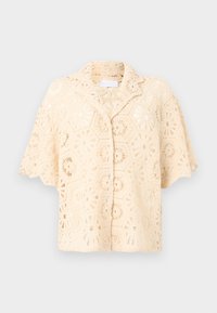 Μπεζ μπλούζα πλεκτή με κοντά μανίκια, που διαθέτει φυτικό εξάγωνο μοτίβο και κλασικό γιακά. Ελαφρύ, αέρινο ύφασμα.