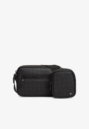 Čierna textúrovaná kabelka cez telo s predným vreckom na zips a pripevnenou menšou kapsičkou, obidve s jemným reliéfnym geometrickým vzorom a malým vlajkovým logom.