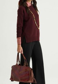 Braune Lederhandtasche mit Chevron-Muster, zwei kurzen Griffen und Fransenakzenten. Die Tasche hat eine strukturierte Form und eine glänzende Textur.