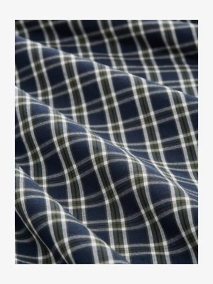 Tissu en tartan bleu, blanc et vert avec des plis doux et une texture tissée visible de près.