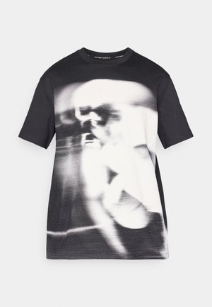 T-shirt noir à manches courtes présentant un imprimé graphique monochrome flou à l'avant. Tissu doux avec un col rond et une coupe standard.