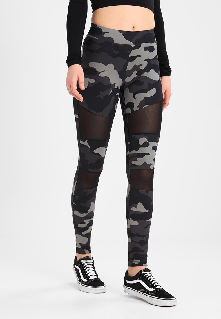 Svart och grå camo leggings med genomskinliga meshpaneler på låren, hög midja och stretchig tyg. Bärs med svarta sneakers.