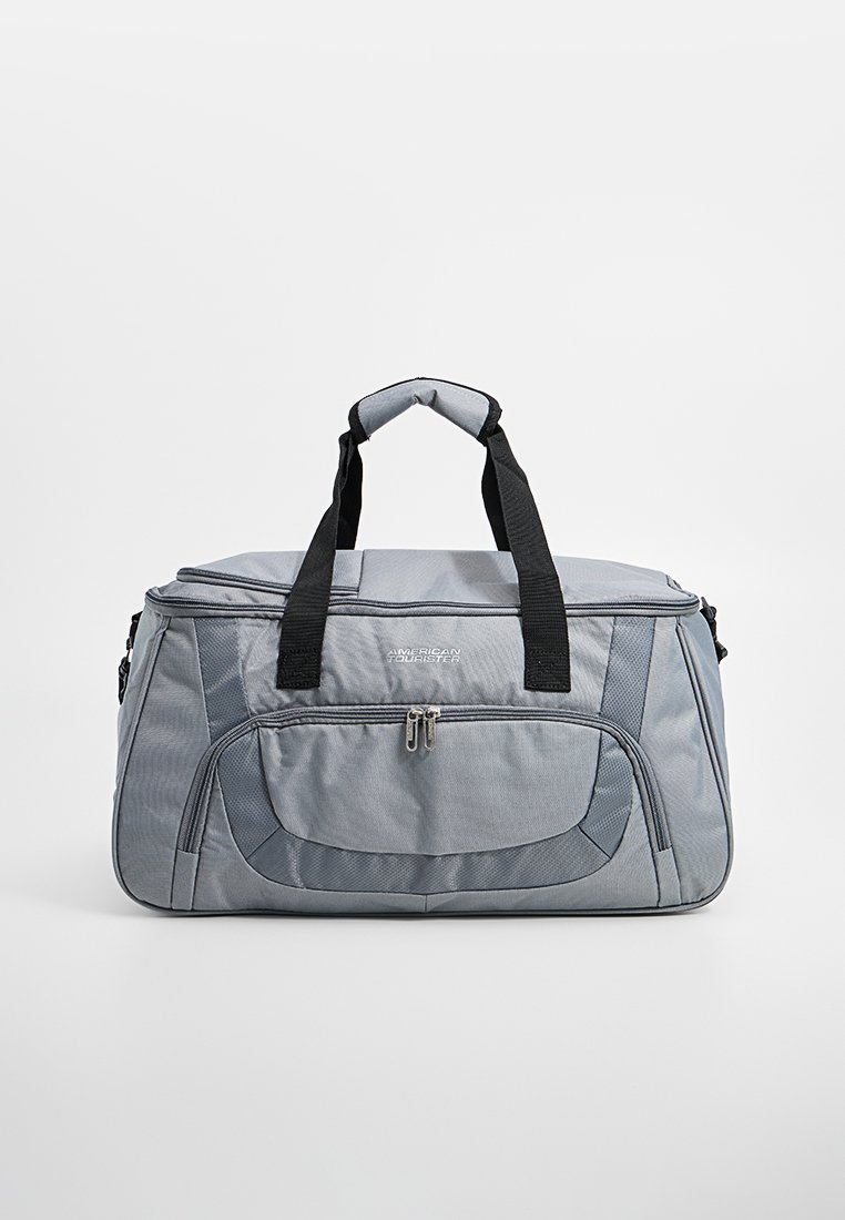 Borsa a tracolla grigia con superficie strutturata, doppie maniglie nere, tasca frontale con zip e dettaglio del logo. Forma rettangolare, adatta per i viaggi.