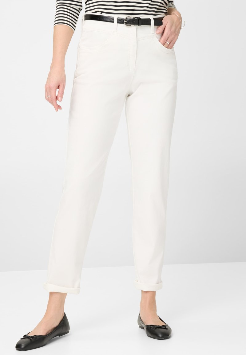 Hvide straight-leg jeans med opfoldet kant, featuring en frontknap og lynlås i lukning, parret med sorte balletflader og en stribet top.