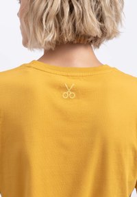Geel katoenen shirt met een decoratief gestikt scharenembleem op de achterkant van de halslijn. Korte mouwen en een relaxte pasvorm.