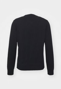 Pulover negru tricotat cu guler rotund, mâneci lungi și manșete cu margini ribbate. Prezintă fante laterale la tiv pentru o mișcare mai ușoară.