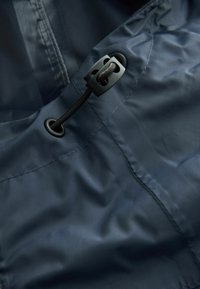 Tissu en nylon bleu marine avec une texture lisse, doté d'un verrou de cordon réglable noir et de détails en œillet, offrant des options de fermeture fonctionnelles.