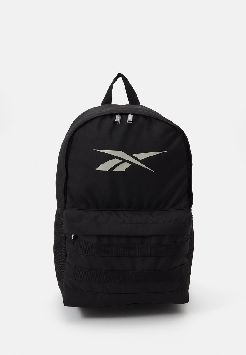 Mochila preta feita de tecido resistente com forma arredondada, apresentando um logótipo prateado, fechos zíper e bolsos laterais em malha para armazenamento.