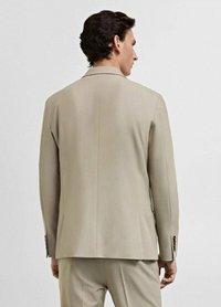 Beige kostymjacka med en skarp krage och långa ärmar, med två knappar på ärmsluten och en slät, skräddarsydd finish.