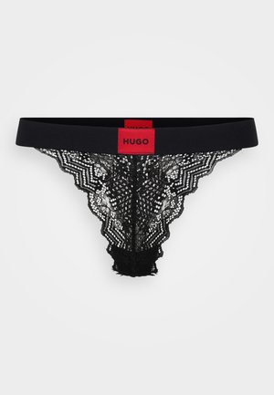 Black lace thong featuring a wide black waistband with a red "HUGO" logo. Intricate lace design with scalloped edges and a soft texture.