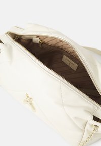 Borsa a tracolla in pelle bianca trapuntata con hardware dorato. L'apertura con zip rivela un interno beige con branding e motivo a righe. Inclusa una catena decorativa.