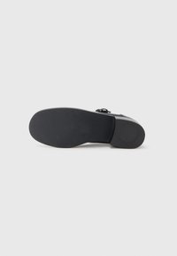 Black footwear with a smooth texture. Flat rubber sole, rounded toe, and a strap across the upper for securing. Minimalist design.