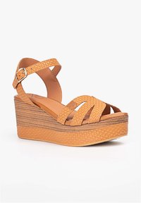 Sandalias de cuña en tono marrón con textura trenzada, que cuentan con un diseño de correas y cierre de hebilla. Suela de plataforma con ranuras horizontales para un mejor agarre.