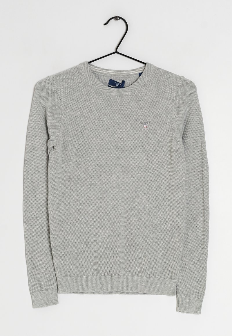 Suéter gris de punto con cuello redondo, puños y dobladillo acanalados, que presenta un pequeño logo en el pecho y un patrón texturizado en toda la prenda.