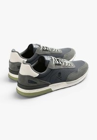 Sneakers in suede e tessuto grigio con dettagli bianchi, punta rotonda, lacci piatti e suola a motivo. Presentano un logo a forma di teschio sul lato.