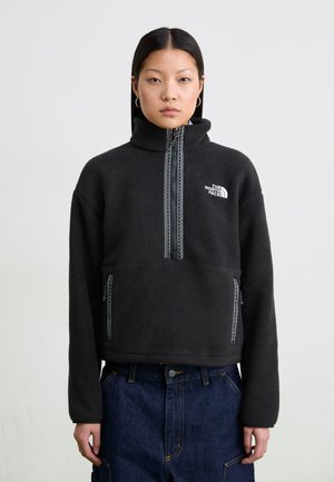 Pullover in pile nero con colletto alto, zip frontale e cuciture a contrasto. Presenta un logo e due tasche frontali con zip.
