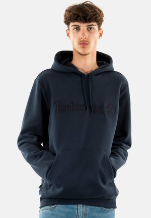 Navy blauwe hoodie van zacht materiaal met een kangoeroezak, verstelbare trekkoordcapuchon en reliëf "Timberland" logo op de borst.