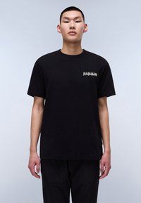 Tricou negru cu mânecă scurtă din bumbac, având un logo mic pe piept. Decolteu clasic și croială lejeră.